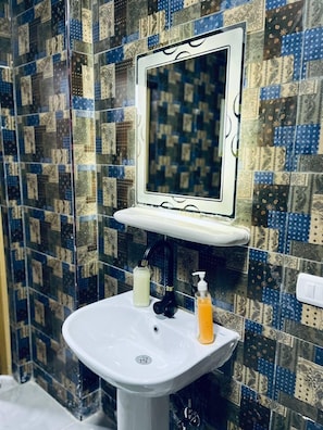 A bathroom with a white sink, a mirror, and patterned tiles on the walls. - four pyramids Guest house (Giza)