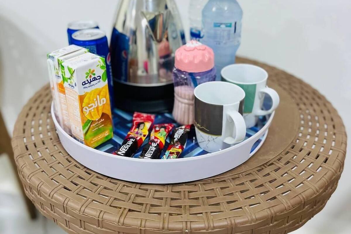 A breakfast tray with juice, coffee, water, and snacks on a wicker table.