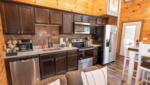 A compact kitchen with dark wooden cabinets, stainless steel appliances, and a granite countertop.
