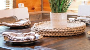A wooden interior with a table set for dining, featuring a woven placemat and a potted plant.