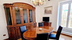 A dining area with a wooden table and chairs, a large cabinet, and a chandelier. - Apartment-Castro Pretorio 2 rooms (Roma)