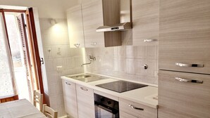 A modern kitchen with a built-in oven, a sink, and wooden cabinets. - Apartment-Castro Pretorio 2 rooms (Roma)