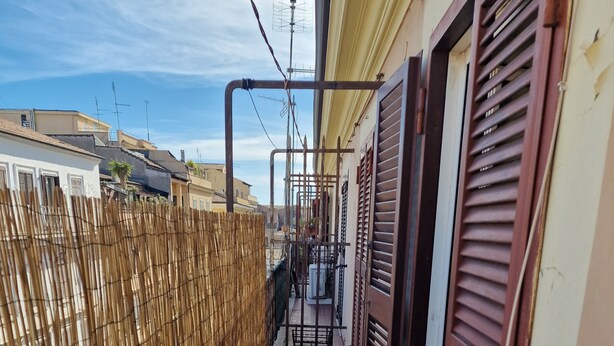 A narrow alleyway with a bamboo fence on one side and a building with shutters on the other. - Apartment-Castro Pretorio 2 rooms (Roma)
