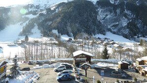 A snow-covered mountain village with a lodge, parked cars, and a clear view of the surrounding mountains. - 3rd floor, parking, tv, ski locker, 38m², Les Contamines-Montjoie (Les Contamines-Montjoie)