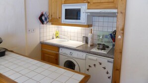 A compact kitchen with wooden cabinets, a microwave, a washing machine, and a sink. - 3rd floor, parking, tv, ski locker, 38m², Les Contamines-Montjoie (Les Contamines-Montjoie)