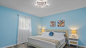 A bedroom with a bed, nightstands, a ceiling fan, and artwork on the wall.