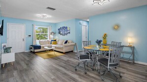 A living room with a sofa, coffee table, and dining table with chairs.