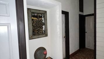 Un pasillo con piso estampado, una pequeña mesa con una vela y un adorno de pared.