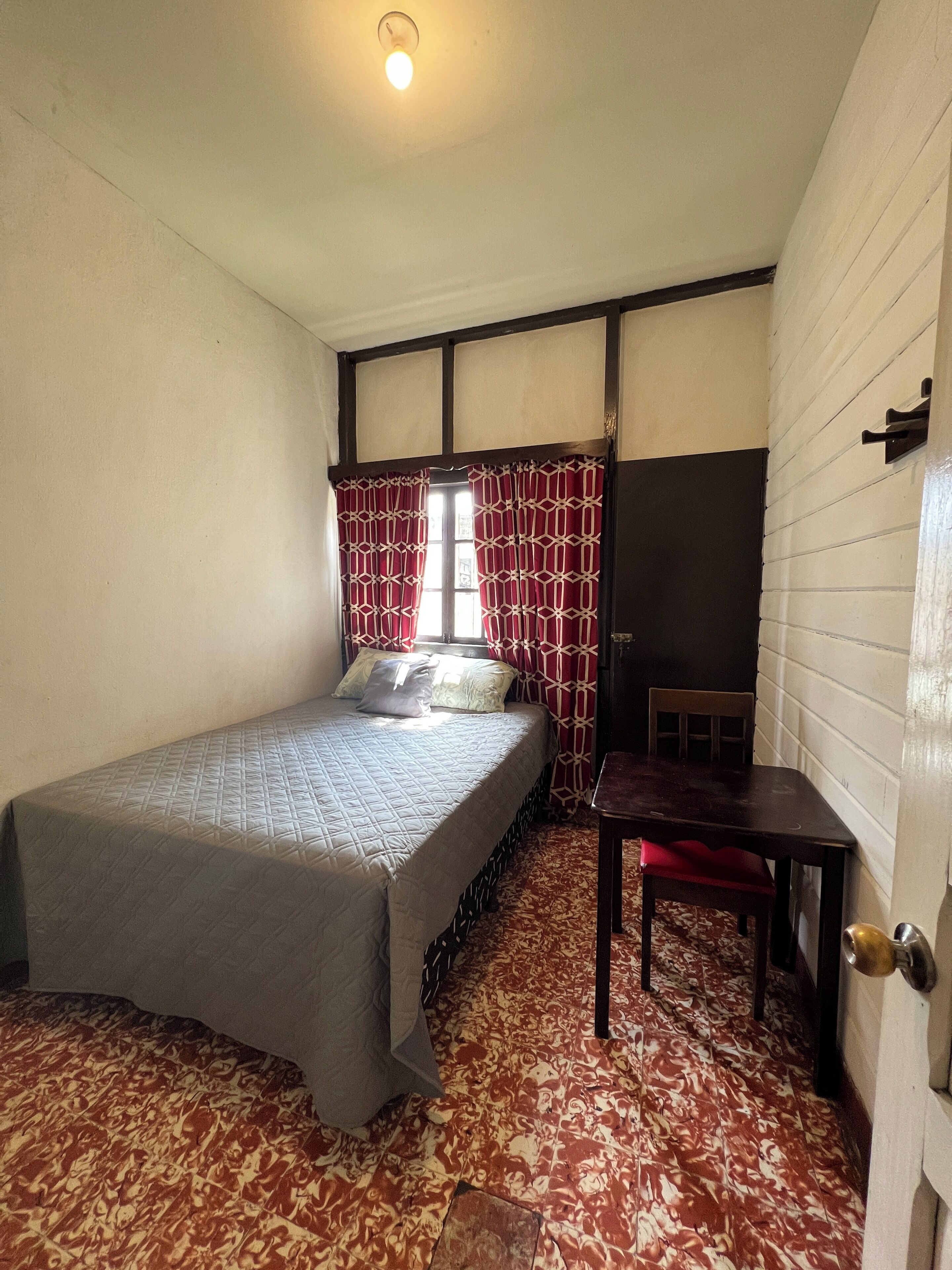 Una habitación pequeña y acogedora con una cama individual, una mesita y una silla.