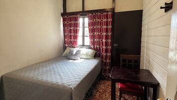 Una habitación pequeña y acogedora con una cama individual, una mesita y una silla.