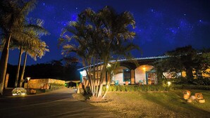 Vista nocturna de un resort con palmeras, un edificio de piedra y un puente al fondo.