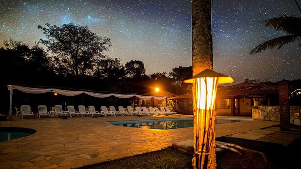 Zona de piscina con sillas de descanso, una carpa y un cielo estrellado.