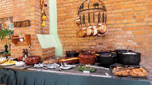 Una mesa de buffet con distintos platos y utensilios de cocina frente a una pared de ladrillo.