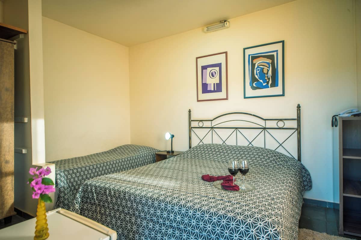 Habitació d'hotel amb dos llits, una taula de nit amb una làmpada i dos quadres al mur.