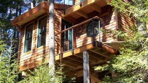 Una cabana de fusta amb un balcó, envoltada d'arbres.