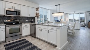A modern kitchen with white cabinetry, stainless steel appliances, and a large island with seating. - Pelican Beach Terrace 307 * 3 bedroom * Salt Water Vacations (Destin)