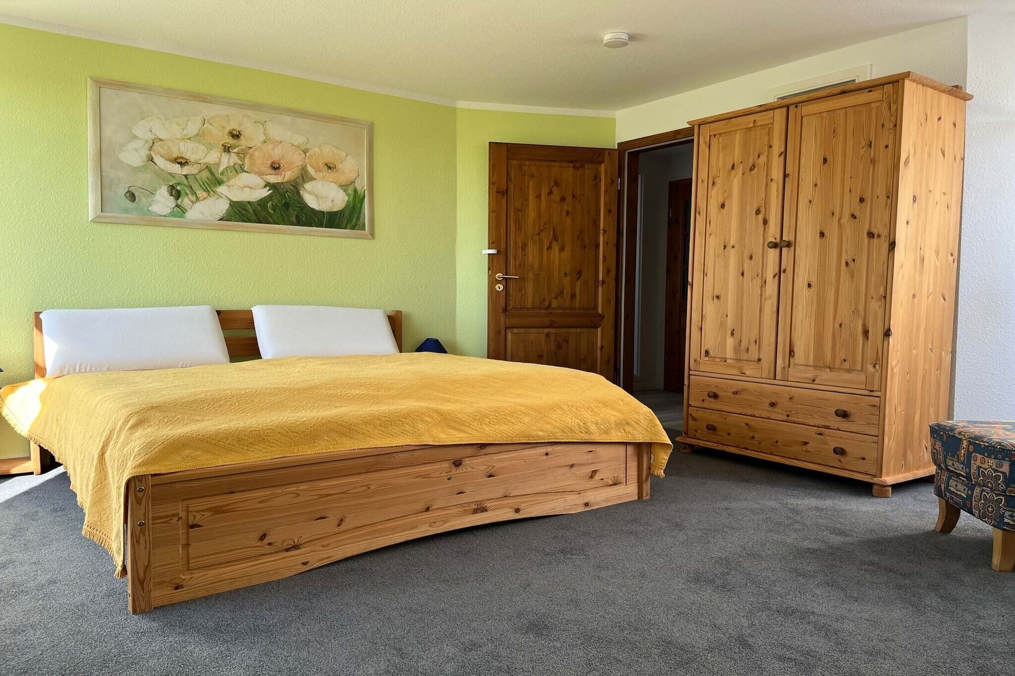 Un dormitorio con una cama de madera, un armario grande y un cuadro en la pared.
