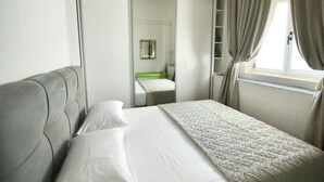 A hotel room with a bed, a wardrobe, and a window with curtains.