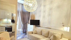A modern living room with a sofa, armchair, and a large chandelier.