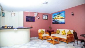 Een receptiezone met een balie, een zithoek en een schilderij aan de muur.