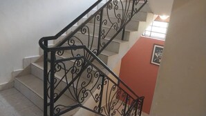 Een trap met sierlijke zwarte metalen leuningen en een rode muur.
