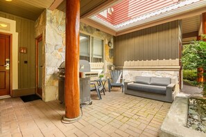 Un espace extérieur abrité, doté d’un barbecue, de sièges et d’un mur en pierre.