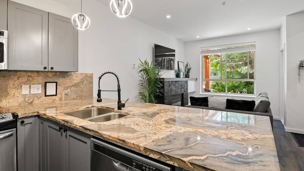 A modern kitchen with granite countertops, stainless steel appliances, and pendant lighting. - Bright Whistler Village 1BR, HotTub, Free Parking, AC (Whistler)