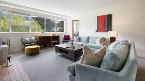 Een moderne woonkamer met een bank, fauteuil, salontafel en een boekenkast.