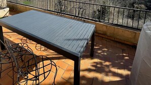 Une terrasse avec une table et des chaises, une vue sur les collines et un ciel dégagé.