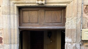 Une entrée en pierre avec une porte en bois et un petit escalier menant à cette porte.