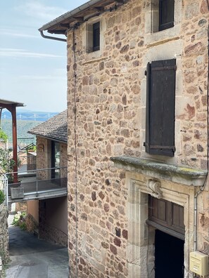 A stone building with a balcony, a fireplace, and a view of a bridge in the background.