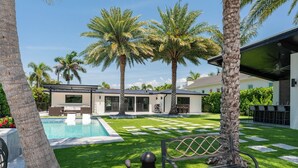 Uma casa moderna com piscina, palmeiras e um espaço de terraço.