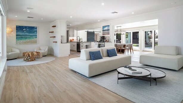 Uma sala de estar moderna com sofá, mesa de centro e área de jantar com cadeiras.