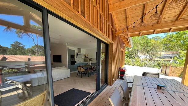 Una cocina moderna con comedor, grandes puertas correderas de vidrio y una terraza de madera.