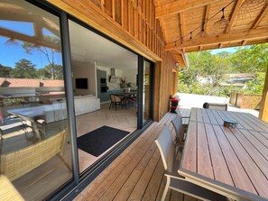 Une cuisine moderne avec un coin repas, de grandes portes-fenêtres coulissantes et une terrasse en bois.