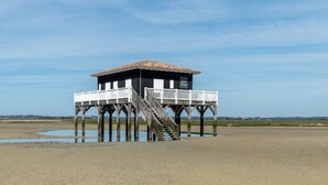 Una estructura de muelle de madera con balcón y escaleras que conducen a un edificio con techo de tejas.