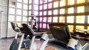 A gym with treadmills, exercise equipment, and large windows allowing natural light. - Studio Living Mercure Liberdade (São Paulo)