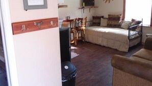 Une pièce confortable avec un lit, un bureau et une chaise. On y trouve un ventilateur de plafond, une télévision et une fenêtre avec des rideaux.