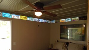 Une chambre à coucher avec un lit, un ventilateur de plafond et une fenêtre donnant sur un immeuble.