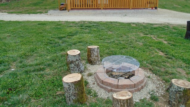 Une cabane en bois avec une véranda et un foyer extérieur.