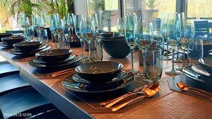 A dining table set with black bowls, clear glasses, and cutlery.