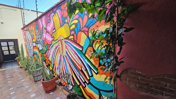 Un mural vibrante en la fachada de un edificio, con una mariposa grande y colorida y diversas plantas.
