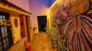 Un callejón estrecho con suelo de baldosas, un mural en la pared derecha y una puerta al final.