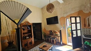 Una sala de estar con un mueble de madera, una mesa de comedor y un televisor montado en la pared.