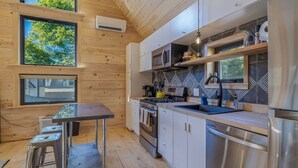 A compact kitchen with wooden walls, a built-in stove, and a sink. - Walkable Studio in Downtown Bar Harbor [Sea Smoke] (Bar Harbor)