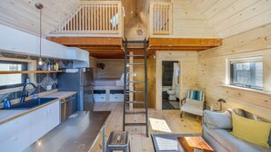 A compact cabin interior with a kitchen, dining area, and a loft bedroom. - Walkable Studio in Downtown Bar Harbor [Sea Smoke] (Bar Harbor)
