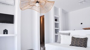 Uma sala de estar moderna e minimalista, com um sofá branco, luminária pendente trançada e uma TV de tela plana na parede.