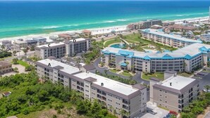 A coastal hotel complex with multiple buildings, a beach, and a clear view of the ocean. - Pool, Splash Pad & Hot Tub, Private Balcony, Close to Beach (Miramar Beach)