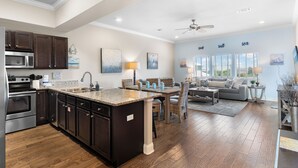 A spacious kitchen with dark wood cabinets, a large island, and a built-in microwave. - Pool, Splash Pad & Hot Tub, Private Balcony, Close to Beach (Miramar Beach)