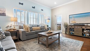 A living room with a grey sofa, a wooden coffee table, and a television on a stand. - Pool, Splash Pad & Hot Tub, Private Balcony, Close to Beach (Miramar Beach)
